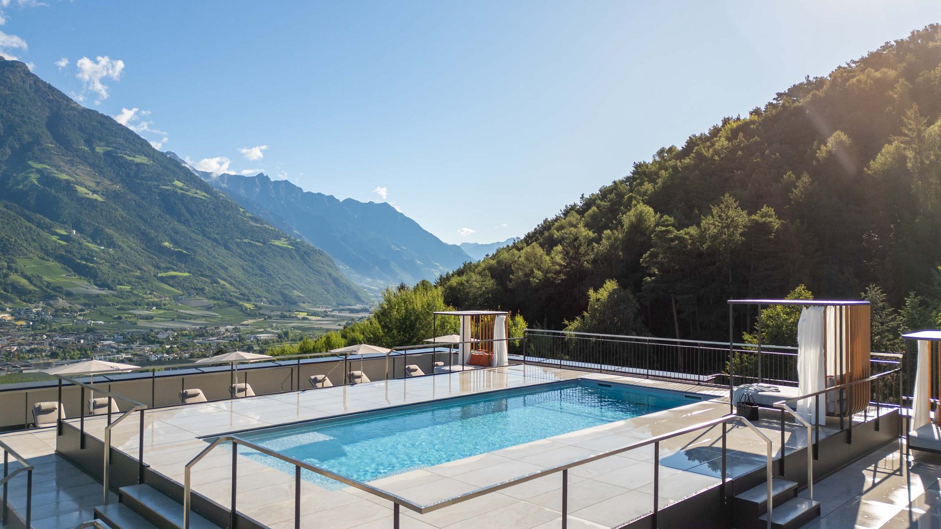 Modernes Schwimmbad mit Bergblick bei sonnigem Himmel