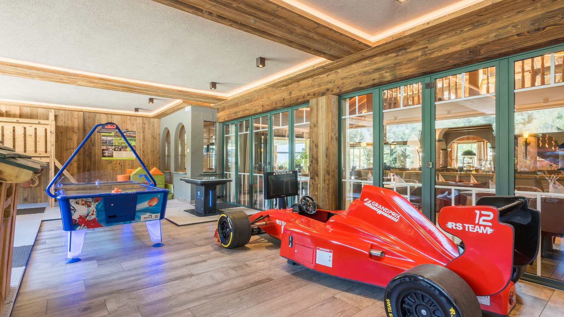 Ramilia: ristorante e appartamenti con aree giochi Sala giochi per bambini con auto da corsa e tavolo da air hockey in legno